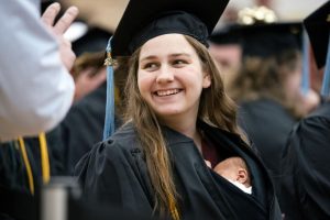 امرأة من ميشيغان تمشي على خشبة المسرح في حفل التخرج الجامعي مع ابنتها البالغة من العمر 10 أيام داخل ثوبها