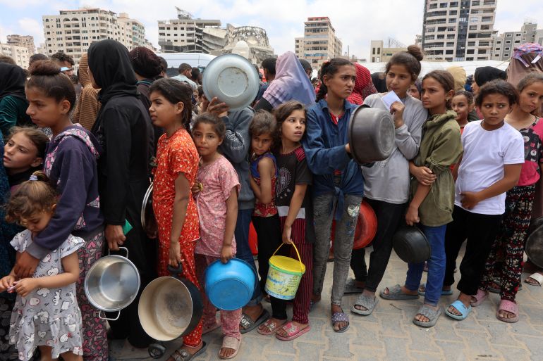 TOPSHOT - Palestinians, most of them children, queue in front of a hot meal distribution truck, at a displacement camp near Gaza City's port on May 22, 2025.