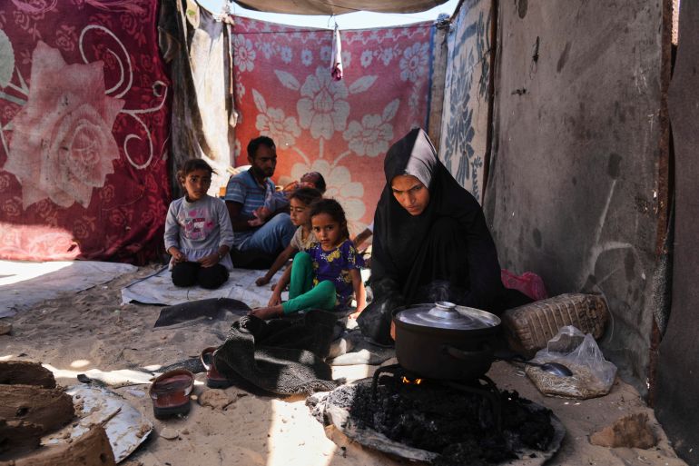 Nouf Al-Arja, 30, who suffers from malnutrition, cooks for her family inside their tent in a camp for displaced Palestinians in Muwasi, Khan Younis, Gaza, Wednesday, May 21, 2025. (AP Photo/Abdel Kareem Hana)